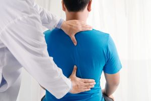 Man having back checked by doctor, doctors hand on low back