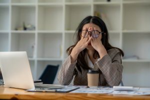 Woman at work desk holding face in hands stressed at work