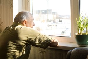 Elderly man alone staring out window