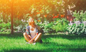 Happy woman sitting in grass with sunny smile