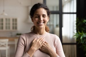 smiling woman with hands on heart and eyes closed