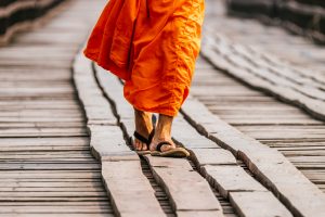 Monk walking on wooden bridge