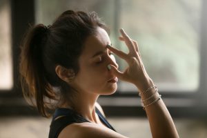 young woman meditating with fingers touching forehead
